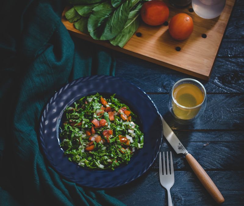 vegetable salad in bowl with fork, knife, and glass