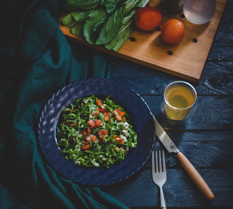 vegetable salad in bowl with fork, knife, and glass