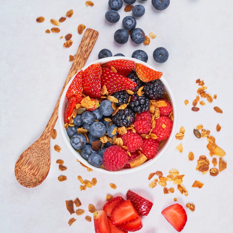 red strawberries and blue berries on white ceramic bowl